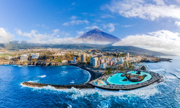 Schwarzer Sandstrand und Kolonialbauten in Puerto de la Cruz mit Bergen im Hintergrund